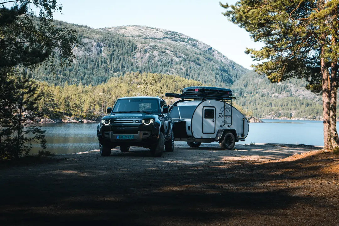 Een avontuurlijke setting met een teardrop minicaravan van HeroCamper. Een prachtige kampeerplek bij een meer met bergen op de achtergrond